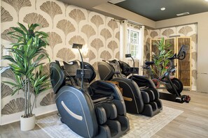 Ein Raum mit Massagesesseln, Laufband und einer Topfpflanze.