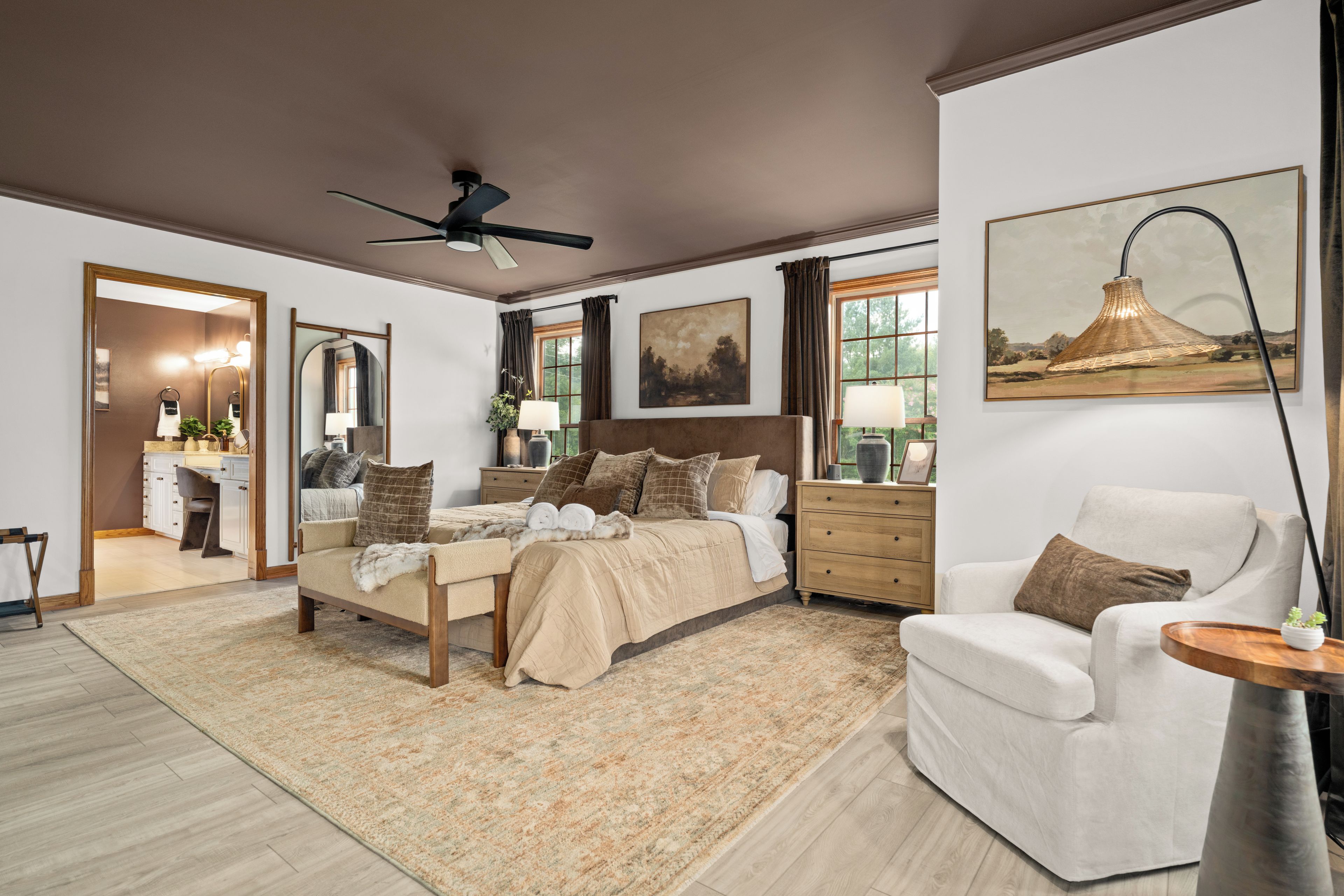 A spacious bedroom with a large bed, a sitting area with a chair, and a dining area with a table.