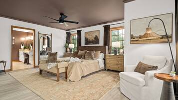 A spacious bedroom with a large bed, a sitting area with a chair, and a dining area with a table.