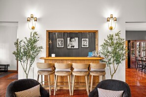 Een bar met een houten toonbank, barstoelen en ingelijste foto's aan de muur.