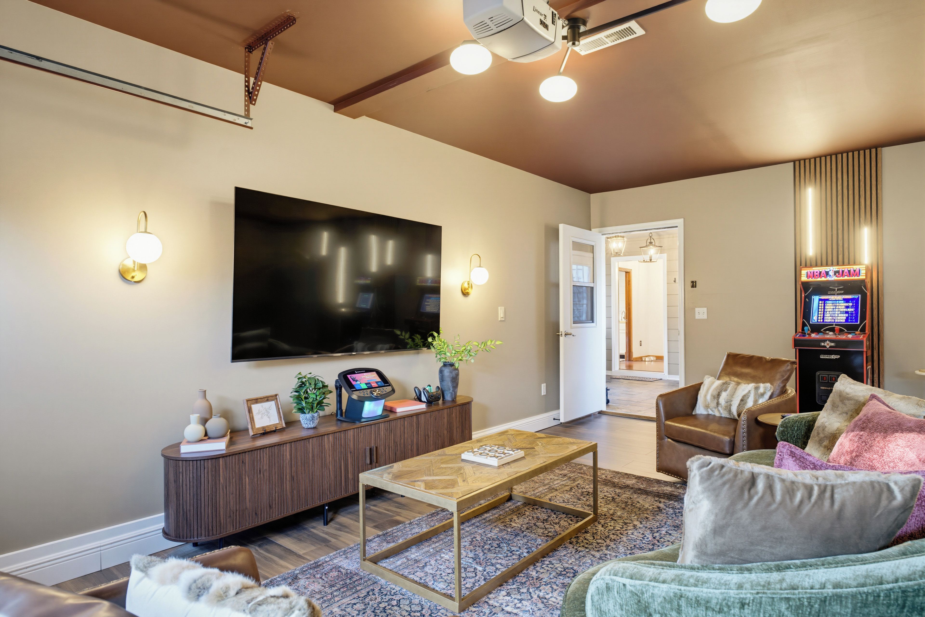 A modern living room with a flat-screen TV, a coffee table, a sofa, and a gaming console.