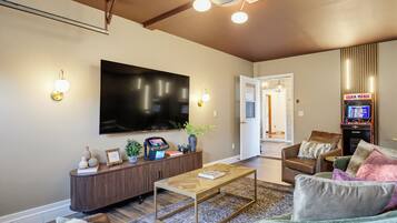 A modern living room with a flat-screen TV, a coffee table, a sofa, and a gaming console.