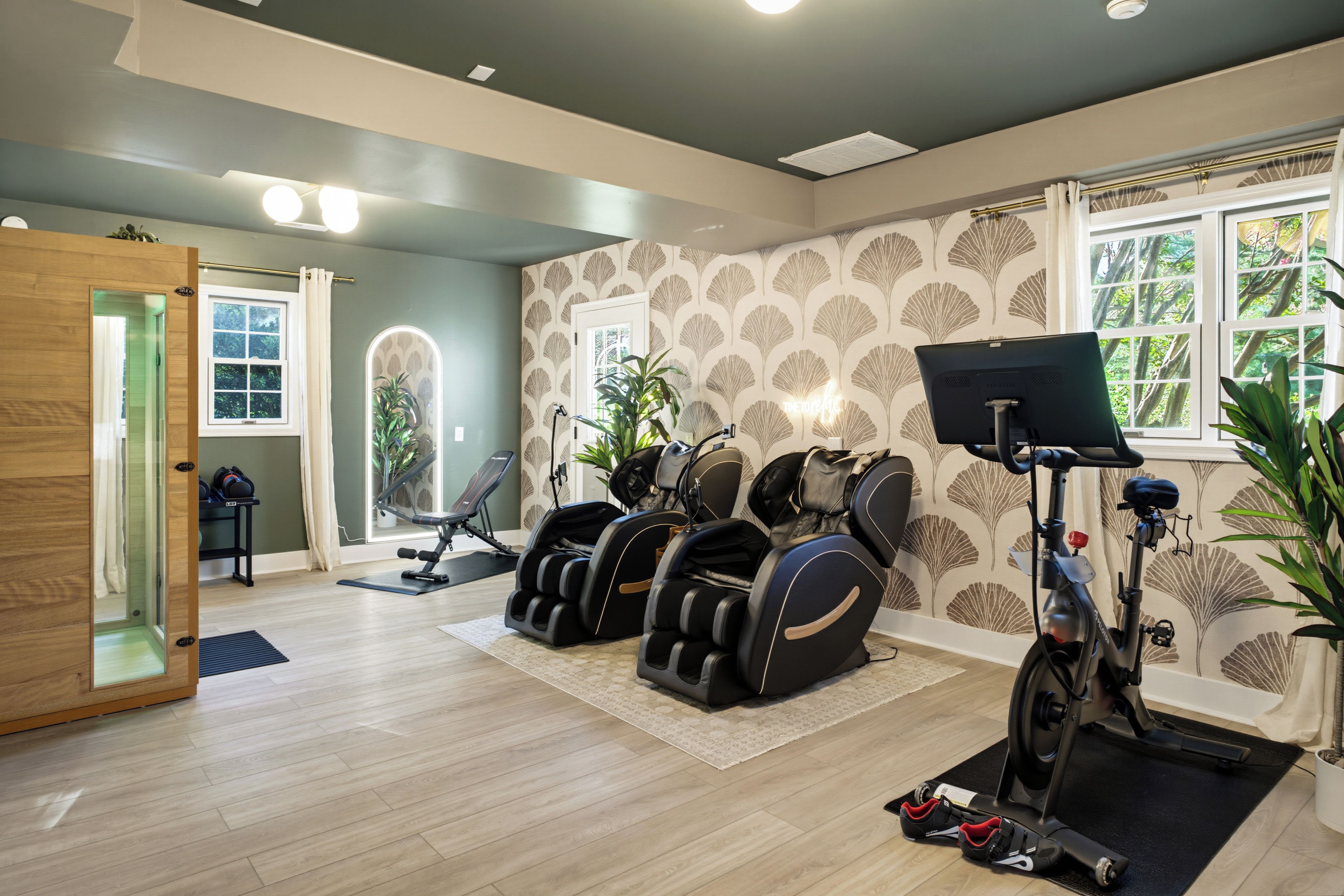 Une pièce équipée d’un fauteuil de massage, d’un vélo d’exercice et d’un tapis de course.