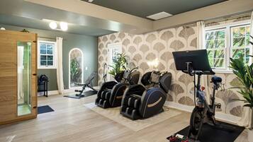 A room with a massage chair, exercise bike, and a treadmill.