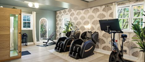 Une pièce équipée d’un fauteuil de massage, d’un vélo d’exercice et d’un tapis de course.