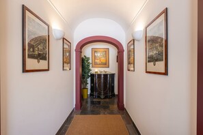 Ein Flur mit gerahmten Kunstwerken an den Wänden, einem zentralen Bogen und einem dekorativen Konsolentisch mit einer Pflanze.