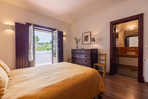 Ein Schlafzimmer mit Bett, Schminktisch, Stuhl und einem durchgegangenen Türspalt erkennbaren Badezimmer.