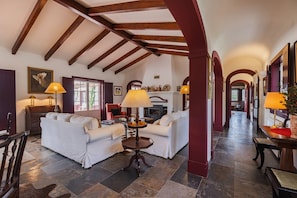 A spacious living area with a fireplace, comfortable seating, and a view of the hallway. - 196 Monte da Palhavã (Montemor-o-Novo)