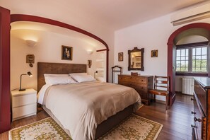 Ein Schlafzimmer mit einem großen Bett, einem Schminktisch, einem Sessel und einem Fenster.