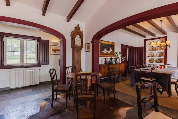 A dining area with a round table, chairs, a clock, and a painting on the wall.