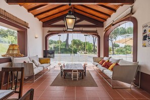 A covered patio area with a wooden ceiling, a table, and two sofas with cushions. - 196 Monte da Palhavã (Montemor-o-Novo)