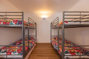 Ein Korridor mit Etagenbetten an beiden Seiten, einer Wandleuchte und Holzboden.