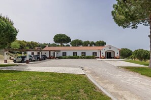 A building with a tiled roof, a covered parking area, and a gravel driveway.