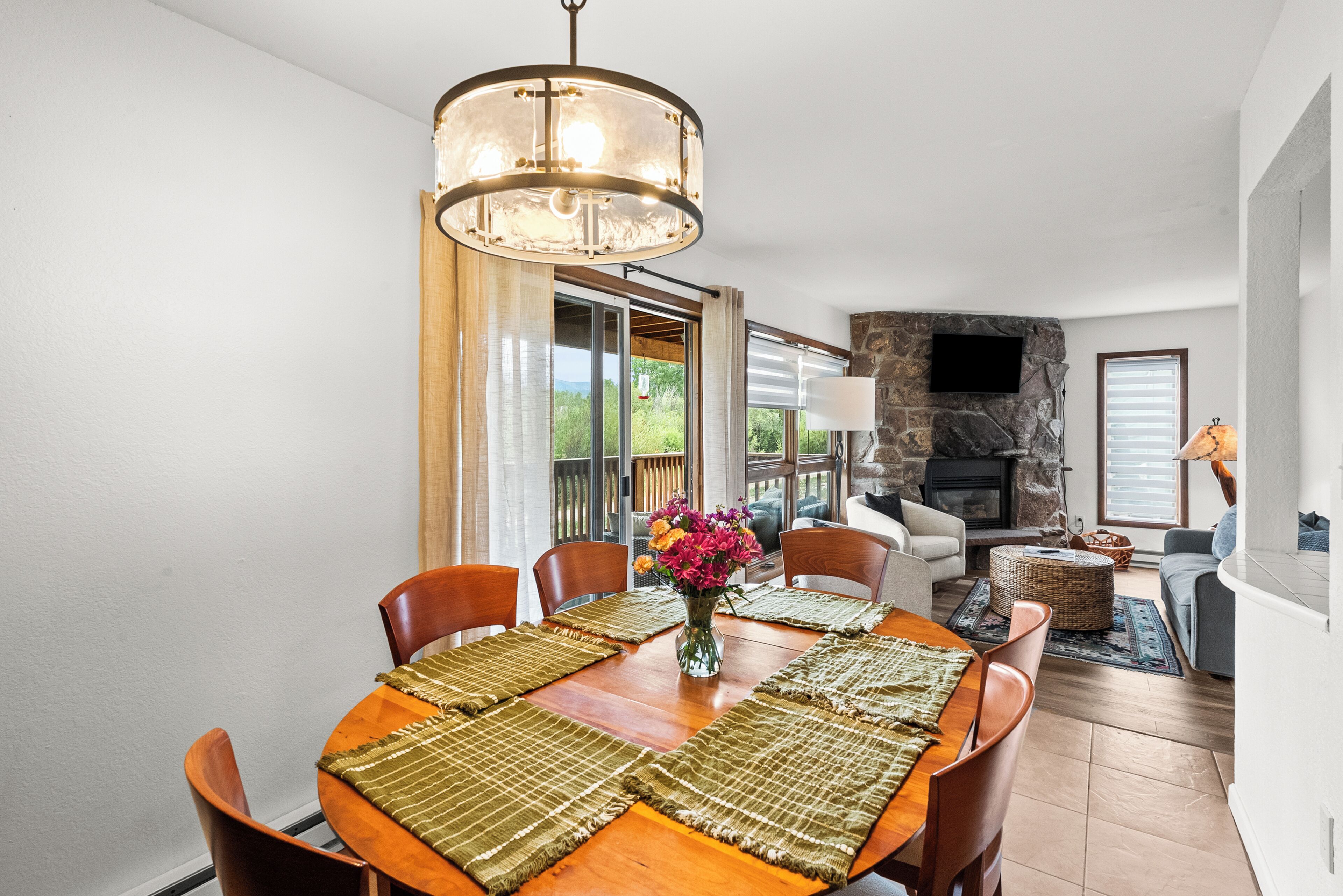 A dining area with a wooden table, chairs, and a chandelier.
