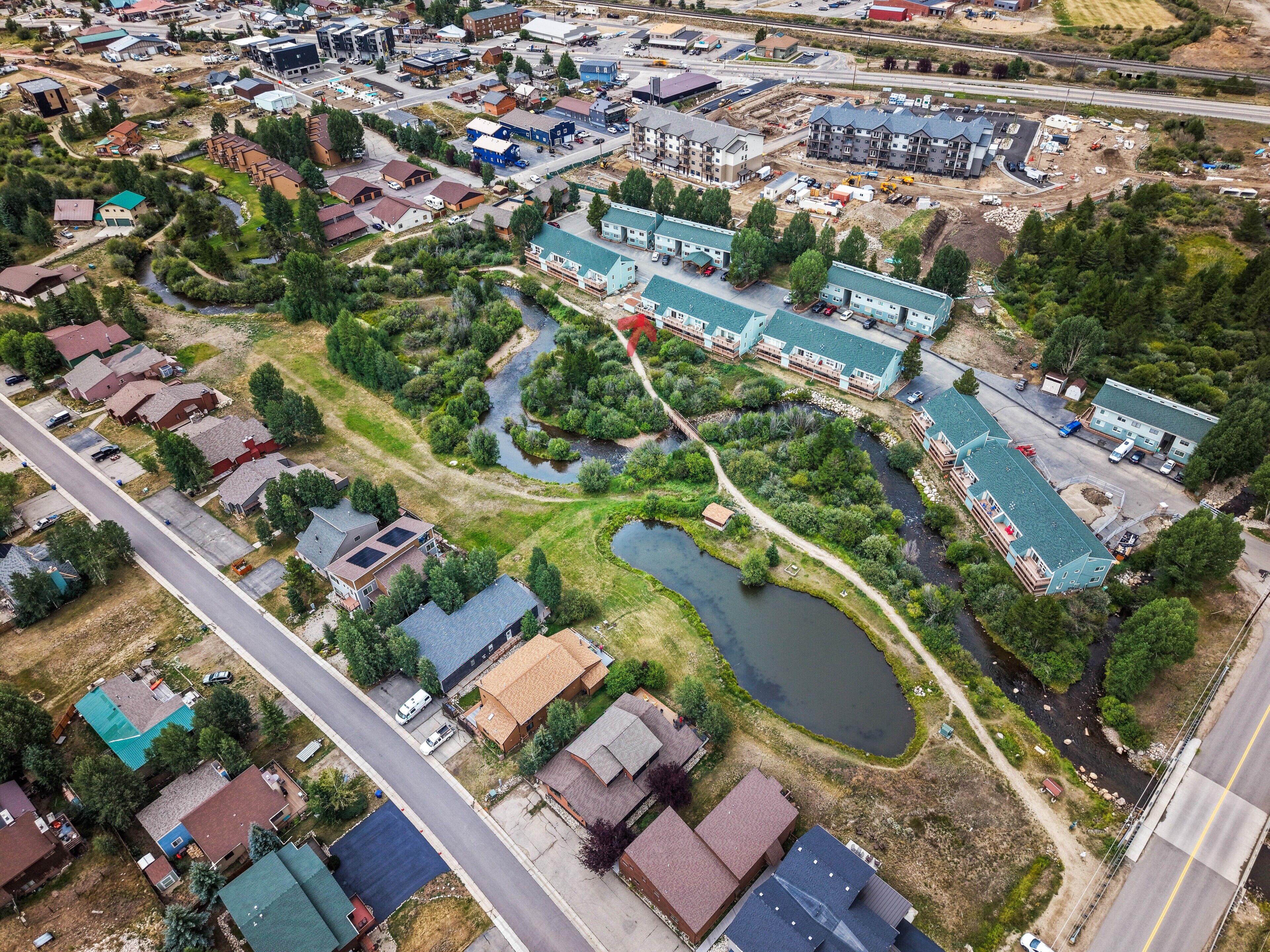An aerial view of a residential area with houses, a small river, and a road.
