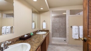 A bathroom with two sinks, a mirror, a shower, and a door with a towel rack. - Big Island Resort Stay Near Kona Coast with Pools & Spacious 1BR Villa (Kailua-Kona)