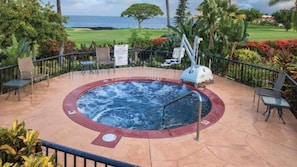 A hot tub surrounded by chairs and a view of the ocean.