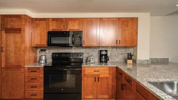 A kitchen with wooden cabinets, a microwave, a stove, a toaster, and a coffee maker.