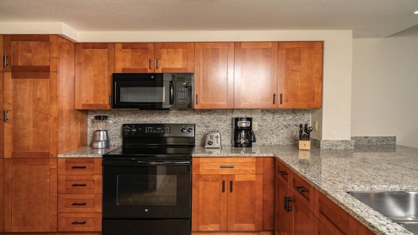 A kitchen with wooden cabinets, a microwave, a stove, a toaster, and a coffee maker.