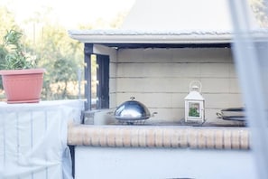 A barbecue grill with a metal cover, a potted plant, and a lantern on a balcony. - Cozy family home with pool near the beach 
Afantou (Αφάντου)