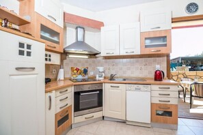 A compact kitchen with white cabinets, a built-in oven, a dishwasher, and a coffee maker. - Cozy family home with pool near the beach 
Afantou (Αφάντου)