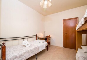 Una cama individual con cabecera, una puerta de madera y una mesita de noche con lámpara.