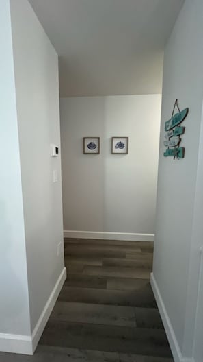 A narrow hallway with wooden flooring, white walls, and two framed pictures hanging on the wall. - Charming Manasota Key Beach Retreat, steps to the beach, sleeps 6 (Englewood)