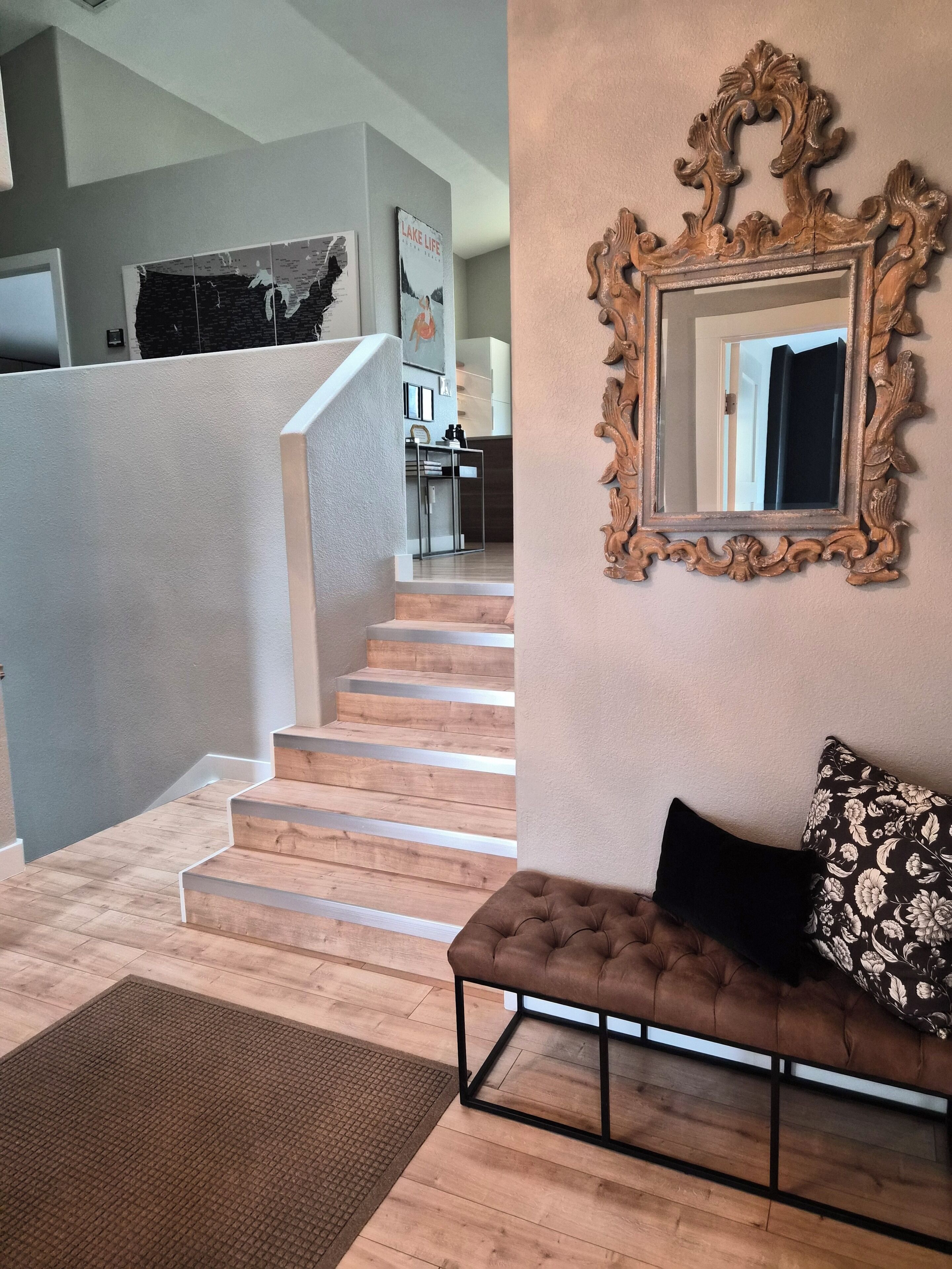 A staircase leading to a landing with a sofa and a mirror on the wall.