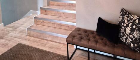 A staircase leading to a landing with a sofa and a mirror on the wall.