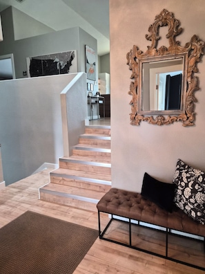 Eine Treppe führt zu einer Zwischenebene mit einem Sofa und einem Spiegel an der Wand.