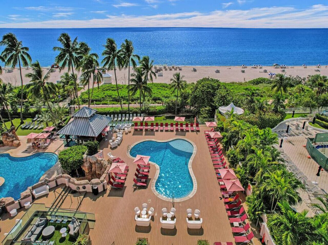 Un resort con diverse piscine, una spiaggia e palme.
