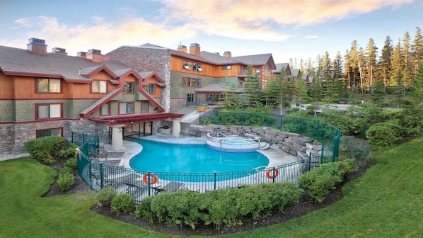 A resort with a swimming pool, stone walls, and a view of trees. - 2BR Suite at WorldMark Canmore-Banff Near Banff National Park & Skiing (Canmore)