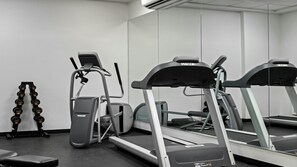 A gym with treadmills, elliptical machines, and a bench.