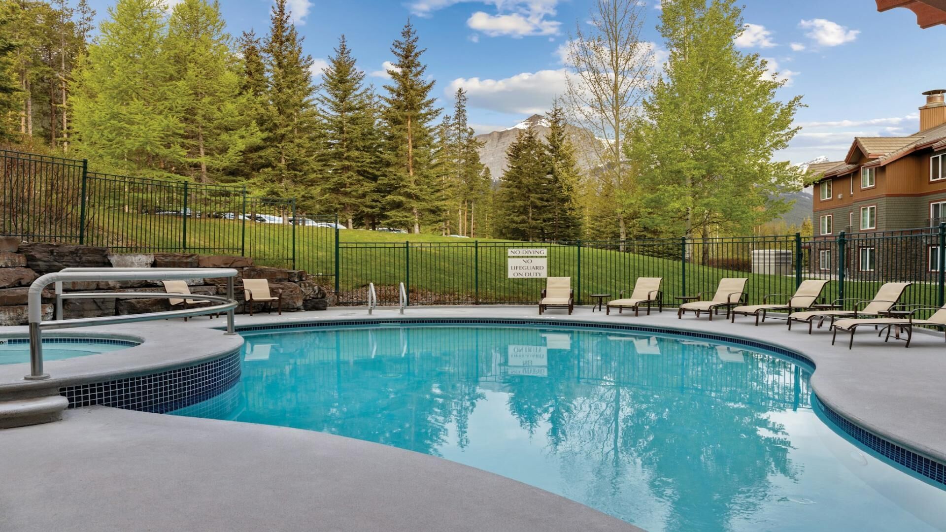 A swimming pool with lounge chairs and a sign prohibiting diving.