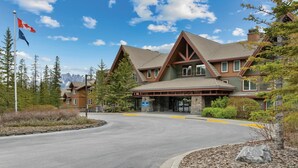 A lodge with a prominent entrance, a flag, and a mountainous backdrop. - 2BR Suite at WorldMark Canmore-Banff Near Banff National Park & Skiing (Canmore)