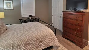 Ein Schlafzimmer mit Bett, Kommode, Deckenventilator und Fernseher.