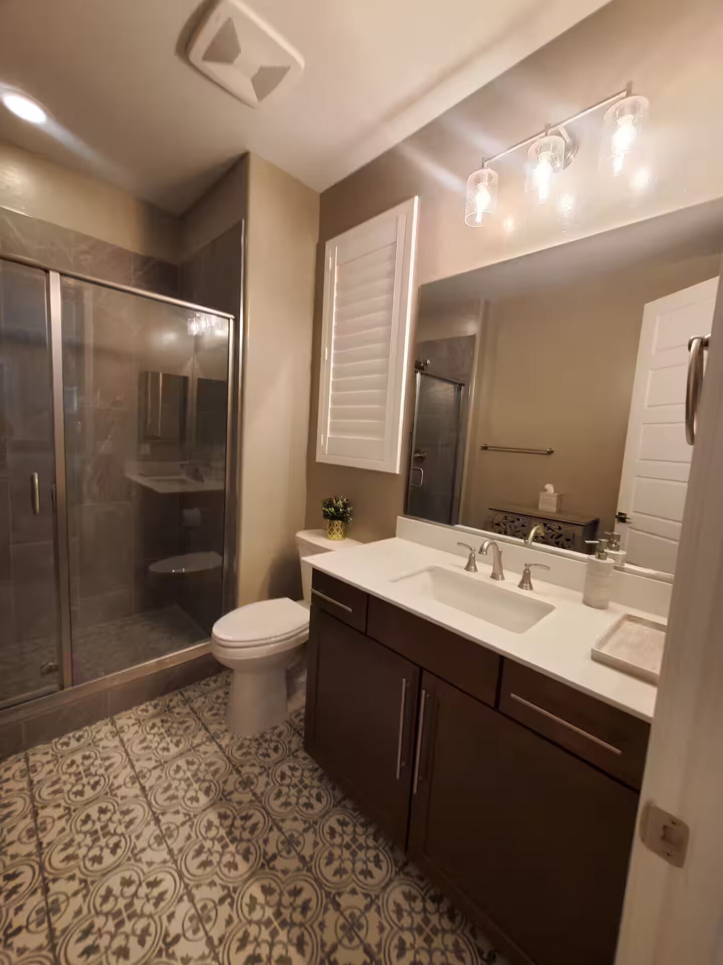 A bathroom with a shower, toilet, sink, and mirror.