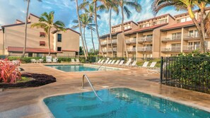Un hôtel doté d’une piscine, de chaises longues et de palmiers.