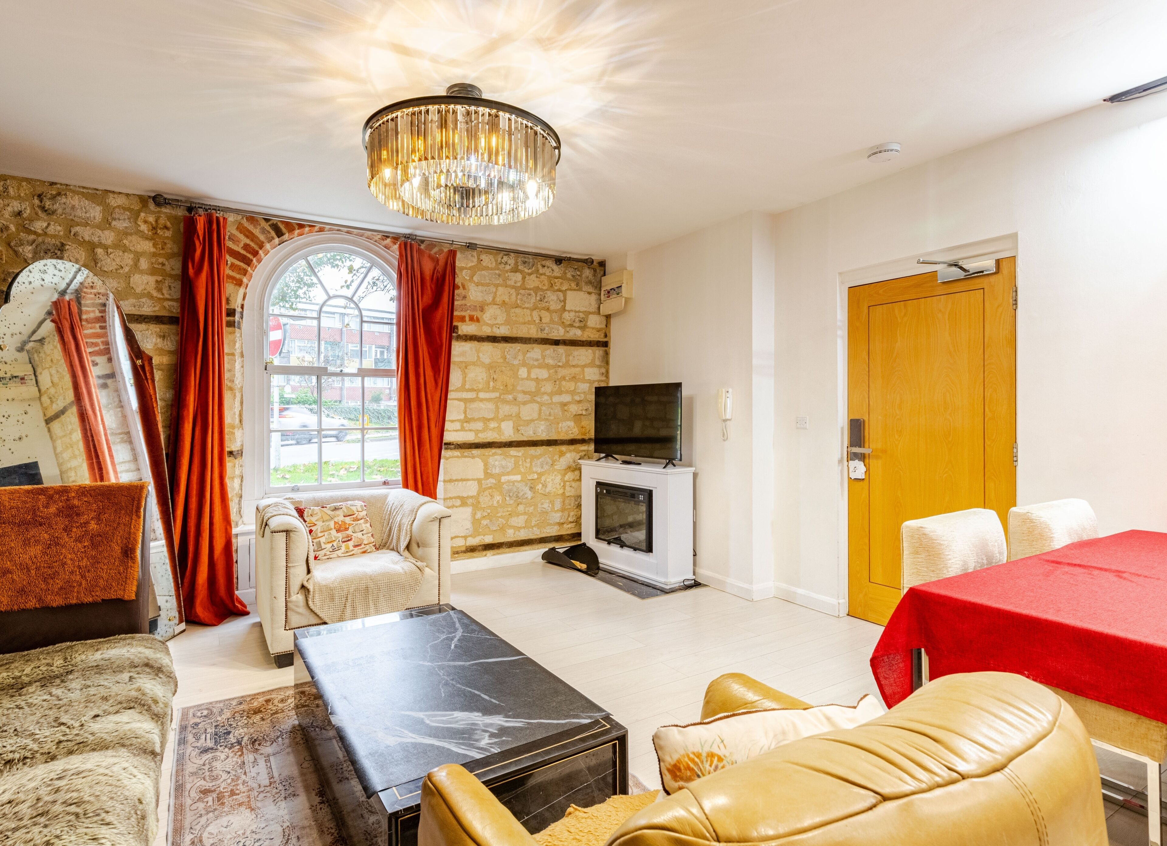 A furnished living room with a fireplace, a television, and a dining table.