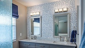 A bathroom with two sinks, a mirror, and a towel rack.
