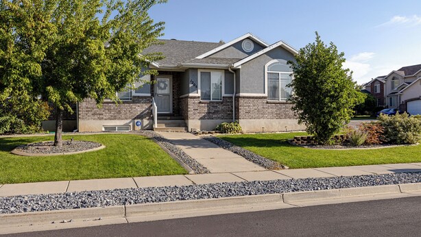 A residential house with a brick facade, a front porch, and a well-maintained lawn.