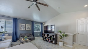 A living room with a sofa, a coffee table, a TV, and a bookshelf.