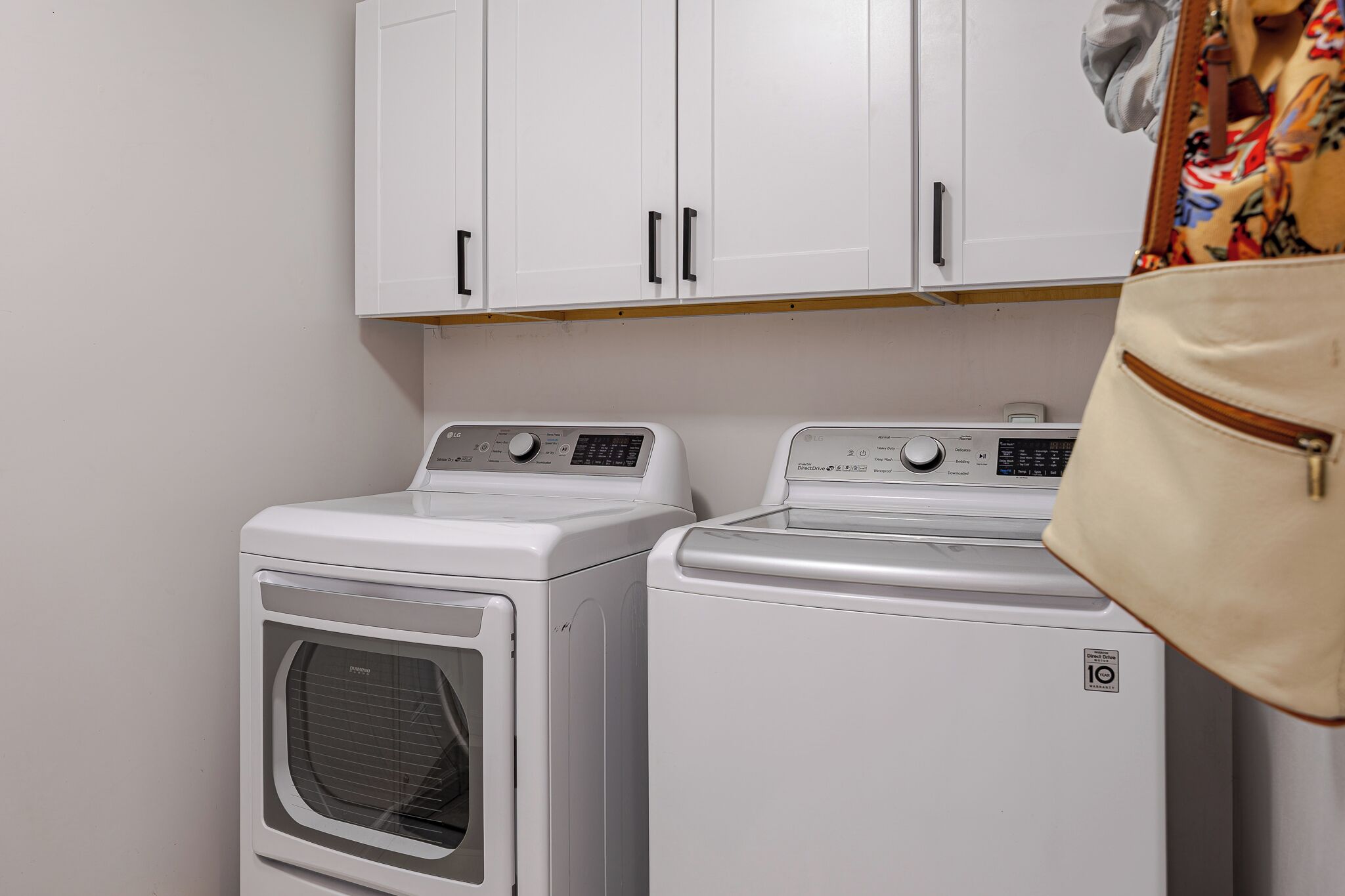 Un espace buanderie avec deux machines à laver blanches et un meuble de rangement au-dessus.