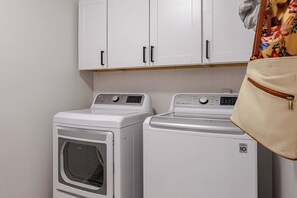 Un área de lavandería con dos lavadoras blancas y un armario encima.