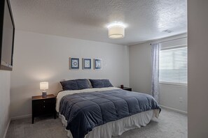 A bedroom with a bed, bedside tables, a lamp, and a clock. - Ogden Adventure Hub-Hike, bike, ski! Sleeps 7, 5 bedrooms, 3.5 bath home. (South Ogden)