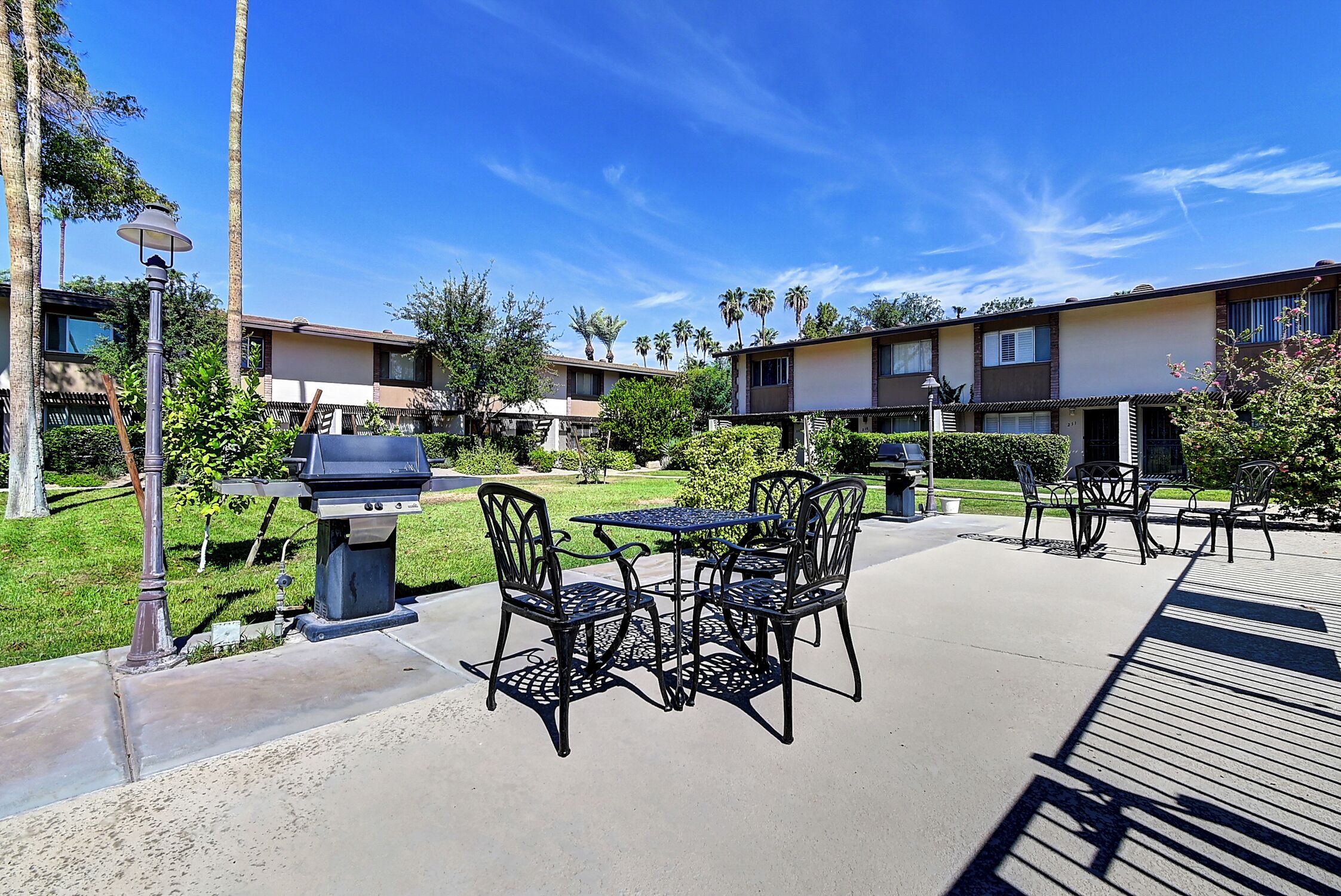 An outdoor patio area with a barbecue grill, tables, and chairs.