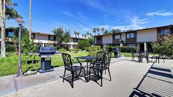 An outdoor patio area with a barbecue grill, tables, and chairs.