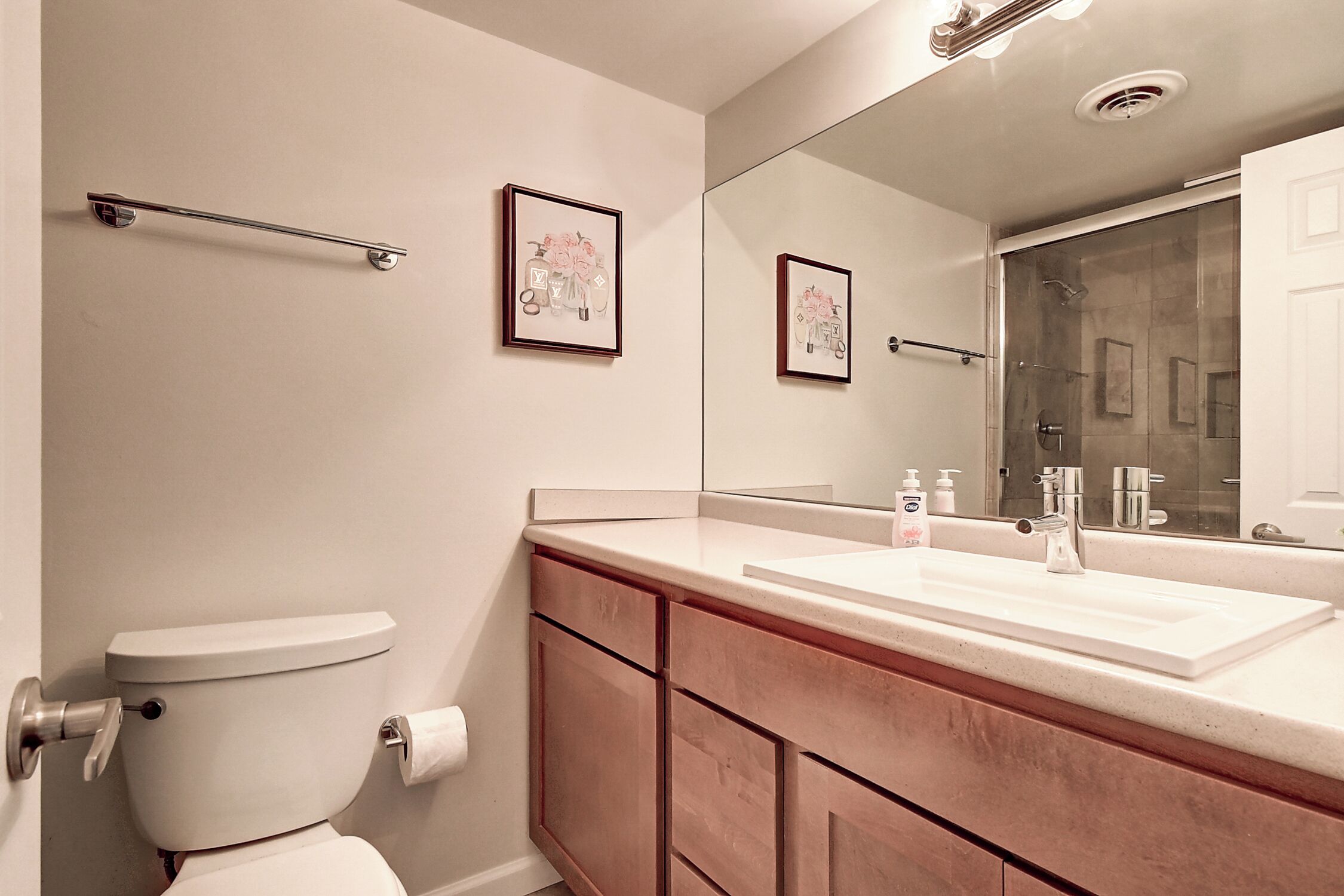 Une salle de bain comprenant des toilettes, un lavabo, un miroir et un tableau encadré au mur.