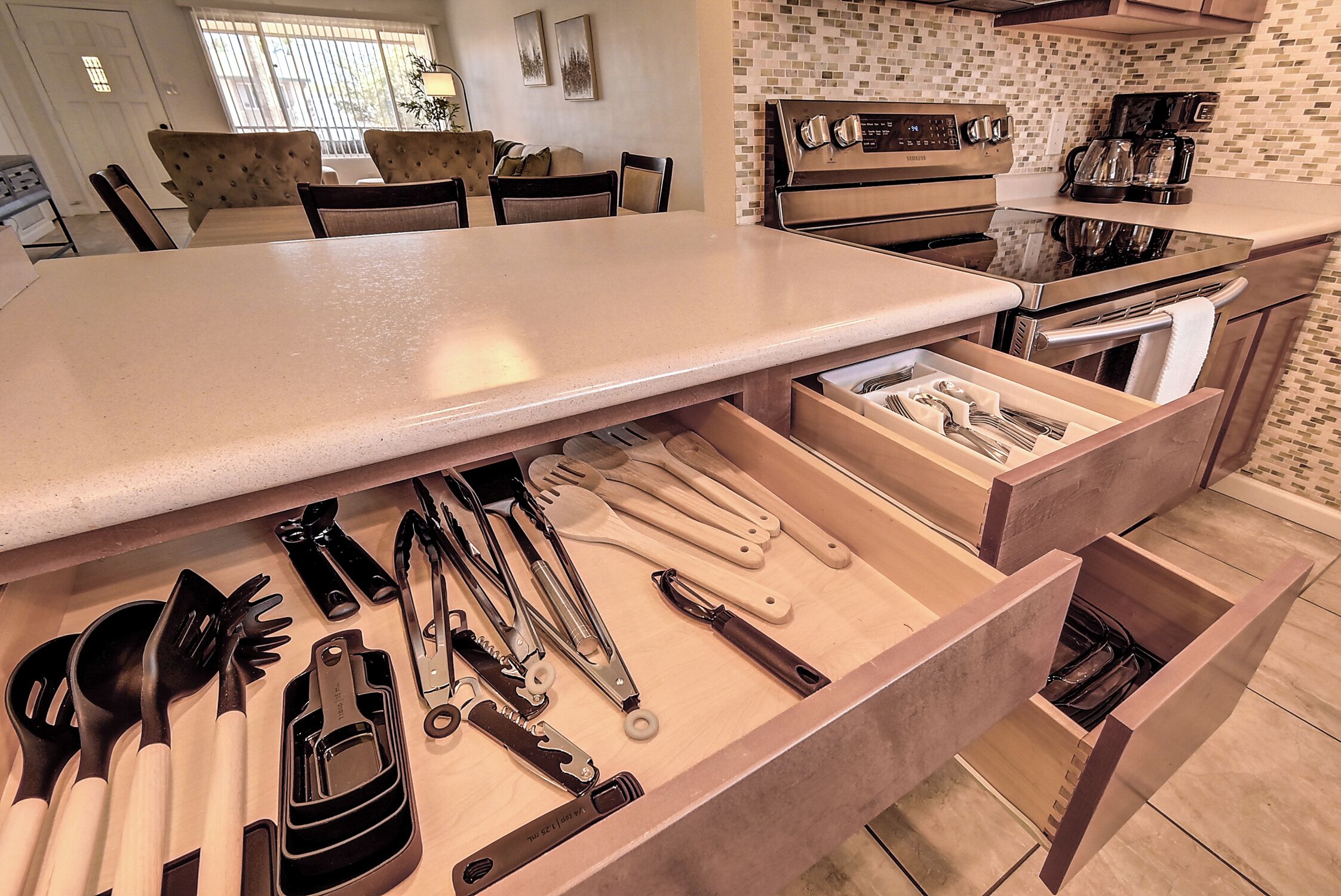 Una cocina con isla integrada, electrodomésticos de acero inoxidable y un organizador de cajones para utensilios.