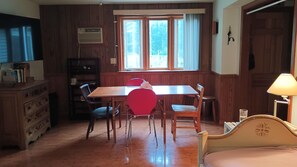 Une pièce comprenant une table à manger en bois, des chaises rouges, un buffet en bois et un lit avec une tête de lit.